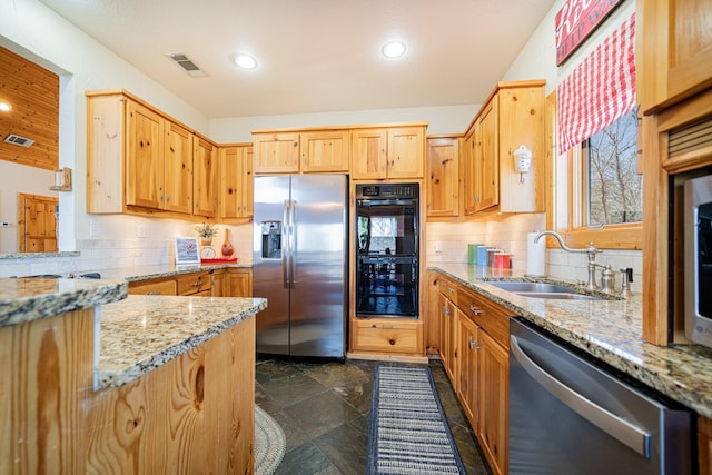 kitchen featuring decorative backsplash, appliances with stainless steel finishes, light stone countertops, and a sink