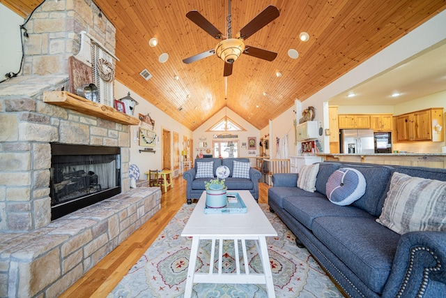 living area featuring light wood-type flooring, visible vents, high vaulted ceiling, wooden ceiling, and a fireplace