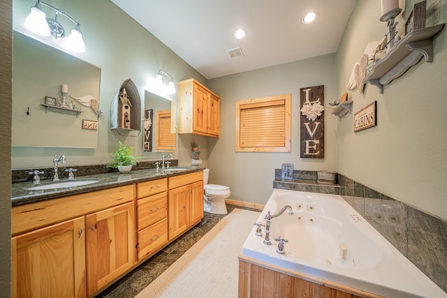 full bath featuring a sink, toilet, a tub with jets, and double vanity