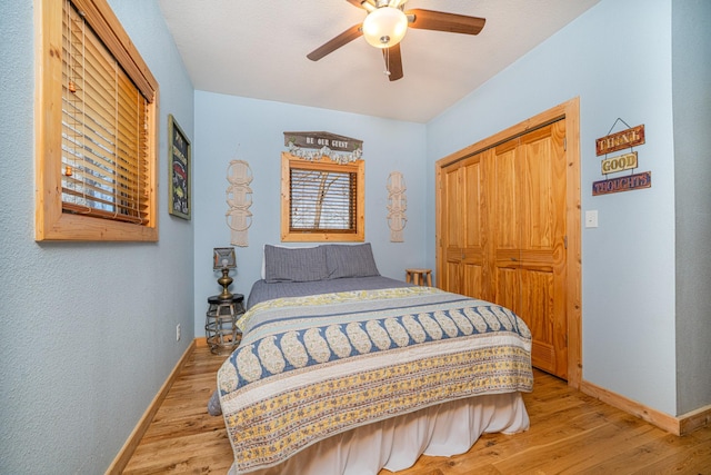 bedroom with a ceiling fan, baseboards, light wood-type flooring, and a closet