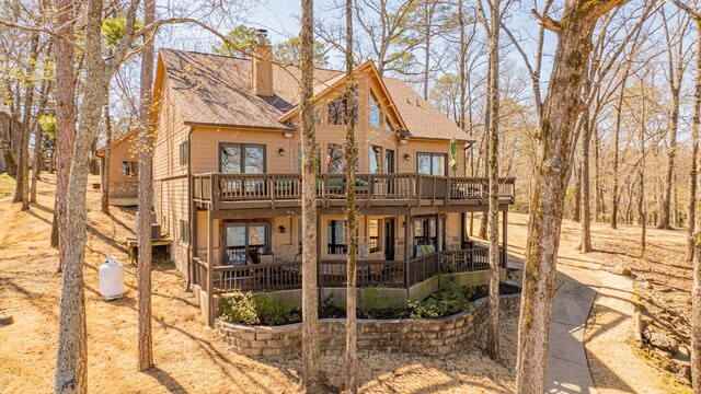 back of property with a deck, roof with shingles, and a chimney