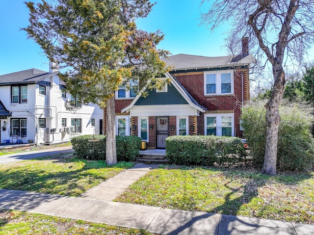 view of property featuring a front yard, brick siding, and a chimney