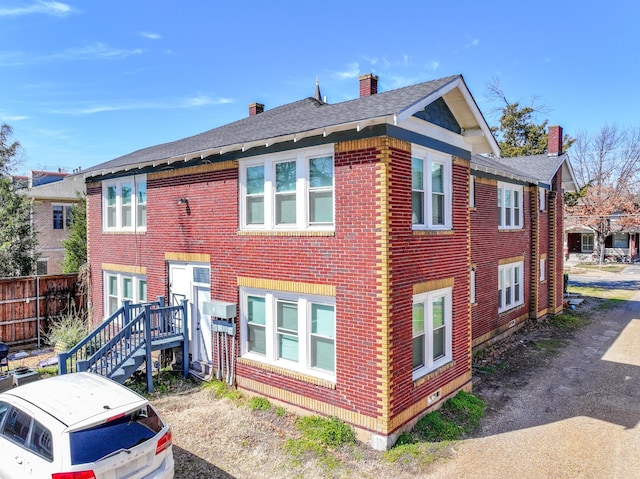 back of property featuring fence, brick siding, and a chimney