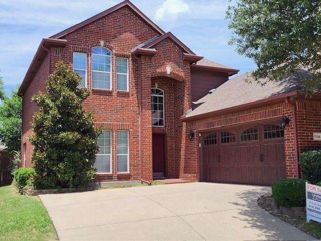 traditional-style home featuring driveway, brick siding, and an attached garage