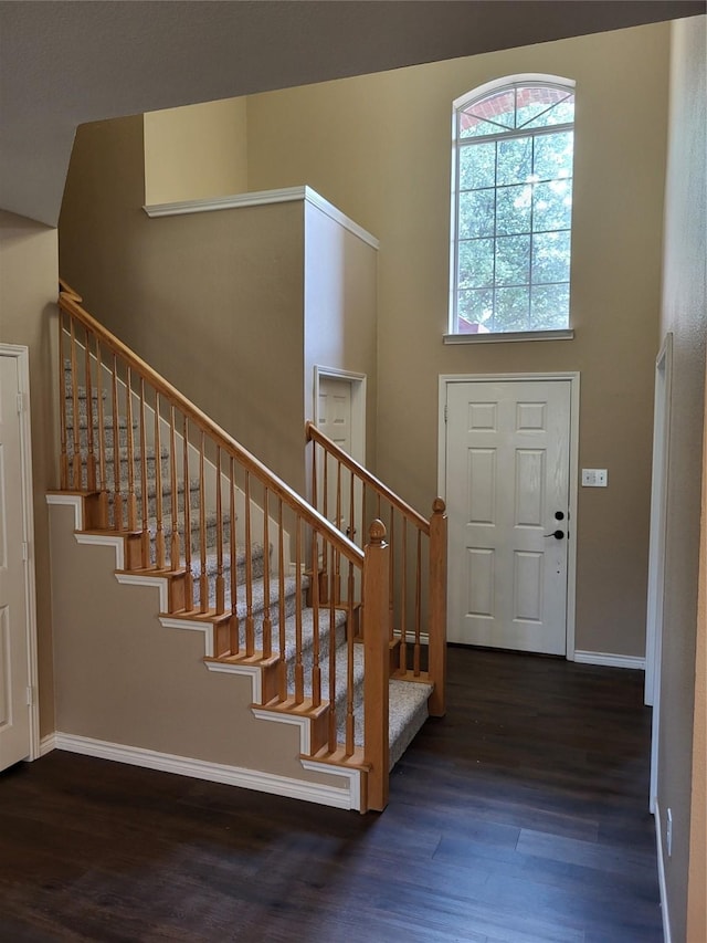 foyer featuring baseboards, stairs, a towering ceiling, and wood finished floors