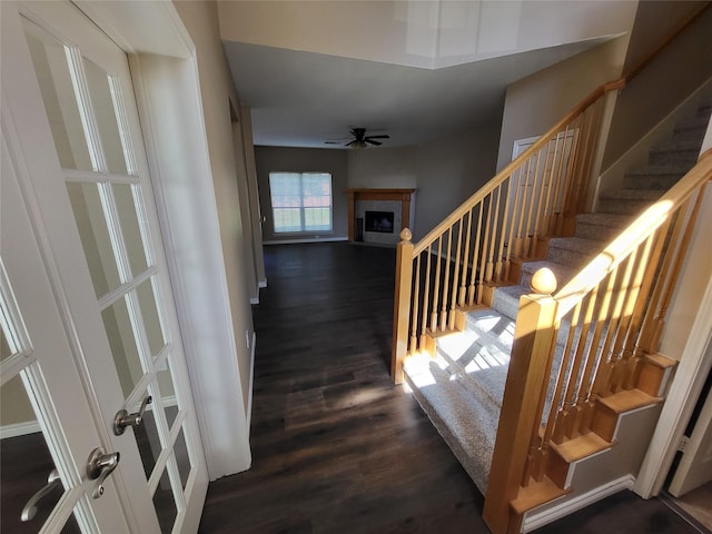 stairs with a fireplace with flush hearth, wood finished floors, and ceiling fan