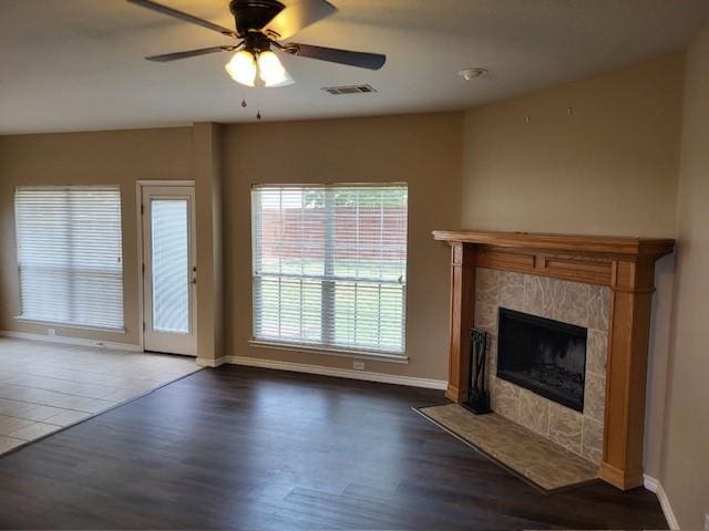 unfurnished living room featuring a ceiling fan, wood finished floors, visible vents, and a high end fireplace