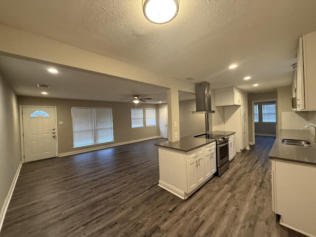 kitchen with dark countertops, wall chimney exhaust hood, electric stove, and a sink