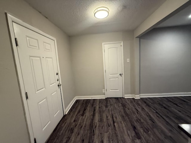 interior space with baseboards, dark wood-type flooring, and a textured ceiling