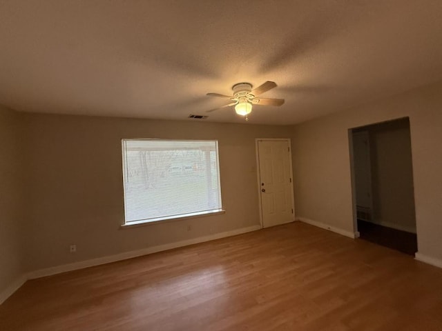 spare room with visible vents, baseboards, light wood-style floors, a textured ceiling, and a ceiling fan