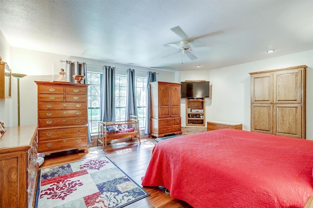 bedroom with light wood-style flooring, a textured ceiling, and ceiling fan