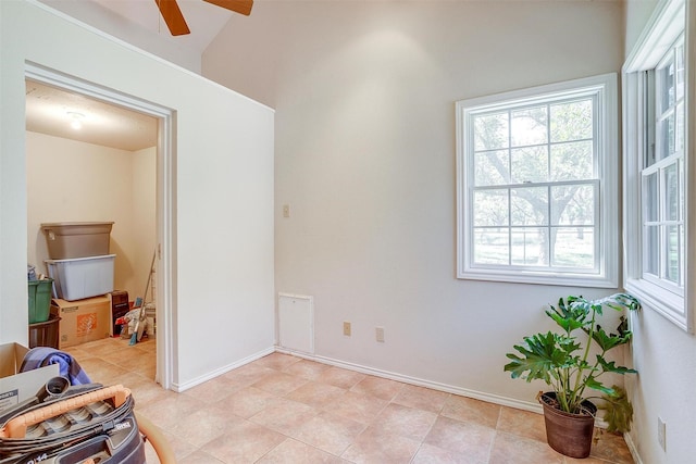 interior space with a ceiling fan, lofted ceiling, and baseboards