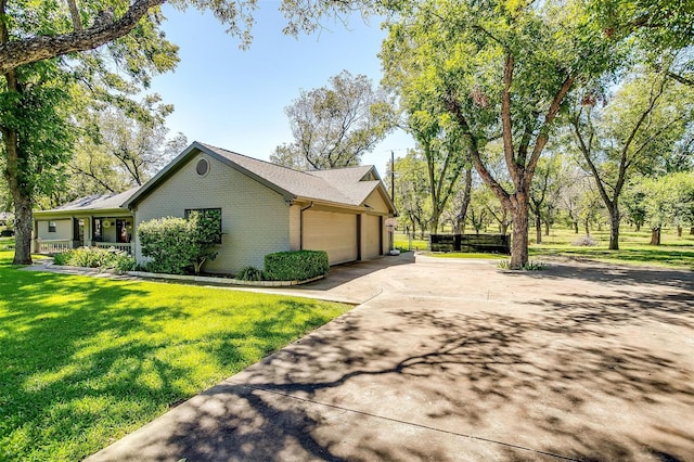 view of side of home featuring concrete driveway, a garage, a lawn, and brick siding