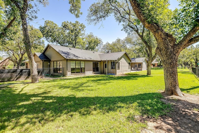 rear view of house featuring brick siding, a yard, and fence