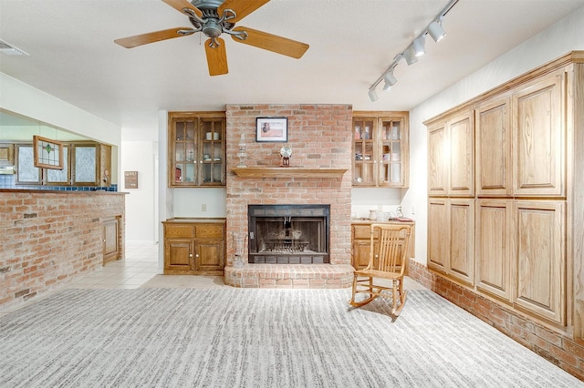 living room featuring visible vents, a brick fireplace, brick wall, light tile patterned floors, and a ceiling fan