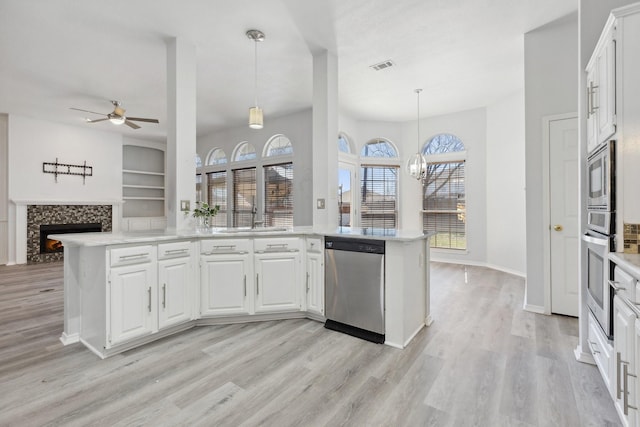 kitchen with visible vents, a lit fireplace, appliances with stainless steel finishes, a peninsula, and a sink