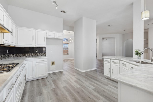 kitchen featuring light wood finished floors, visible vents, white cabinets, and a sink