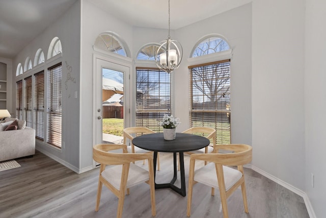 dining space with wood finished floors, baseboards, and a chandelier