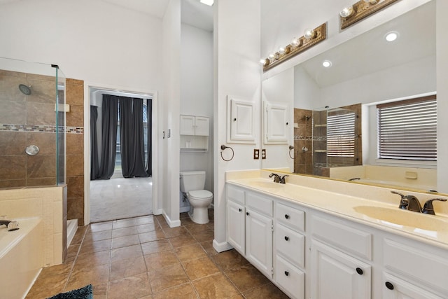 full bath featuring double vanity, toilet, tiled shower, and a sink