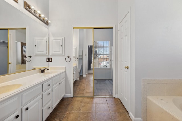 bathroom featuring double vanity, a garden tub, baseboards, and a sink