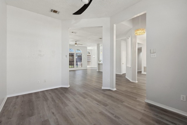 unfurnished room with baseboards, visible vents, dark wood-style flooring, and a textured ceiling