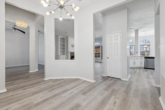 unfurnished dining area with a notable chandelier, light wood-style floors, and a lit fireplace