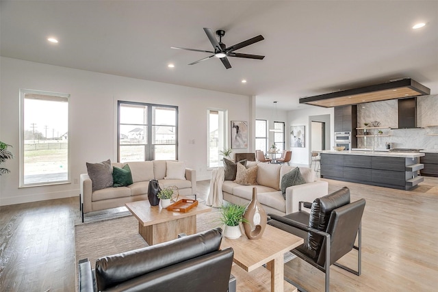 living room with light wood-style flooring, recessed lighting, baseboards, and a healthy amount of sunlight