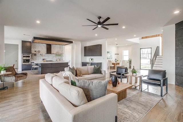 living area featuring recessed lighting, stairs, light wood-type flooring, and a ceiling fan