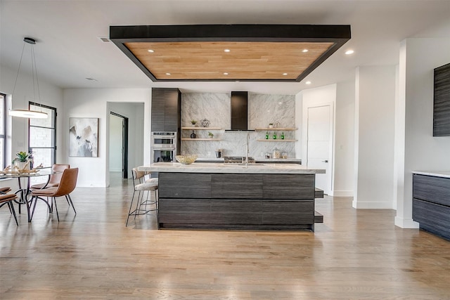 kitchen with open shelves, double oven, wall chimney exhaust hood, modern cabinets, and backsplash