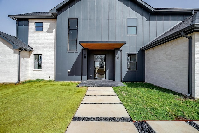 entrance to property featuring brick siding, board and batten siding, and a lawn