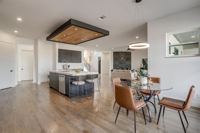 dining area featuring visible vents, stairs, recessed lighting, a fireplace, and light wood-style floors