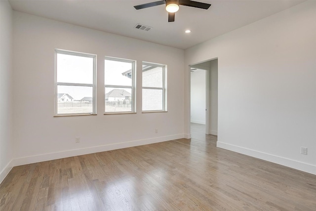 spare room with visible vents, light wood-style flooring, a ceiling fan, and baseboards