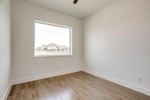 spare room featuring baseboards, light wood-type flooring, and ceiling fan