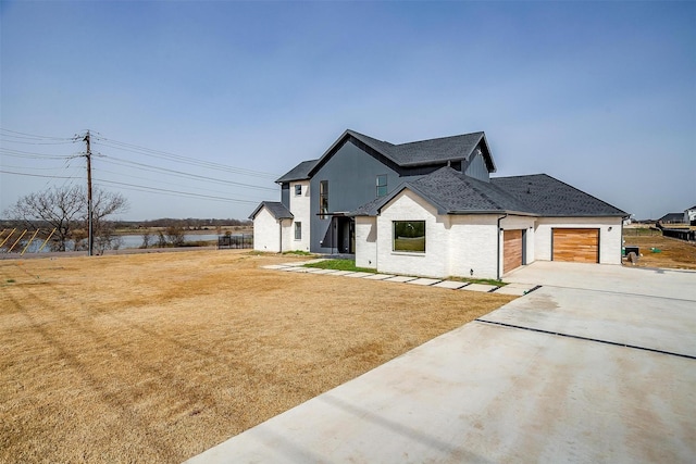 modern inspired farmhouse featuring driveway, a front yard, a shingled roof, a garage, and brick siding