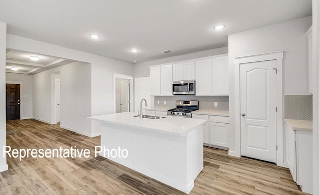 kitchen featuring light wood finished floors, stainless steel appliances, light countertops, and a sink