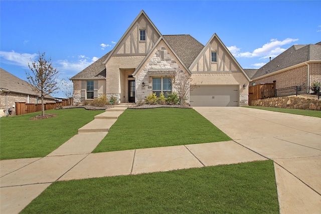 tudor house featuring stucco siding, a front lawn, fence, concrete driveway, and a garage