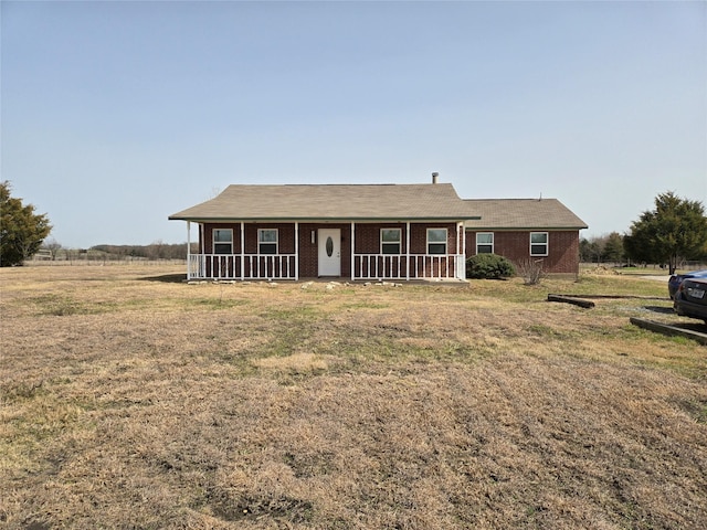 single story home featuring brick siding, covered porch, and a front lawn