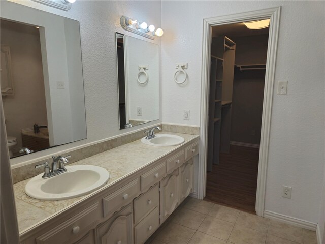 full bath with tile patterned floors, a spacious closet, double vanity, and a sink