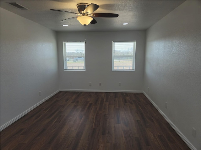 unfurnished room with baseboards, visible vents, dark wood-style flooring, ceiling fan, and a textured ceiling