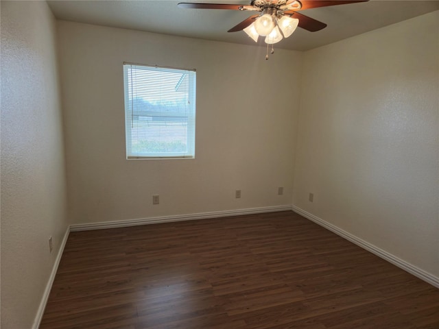 spare room featuring dark wood finished floors, a ceiling fan, and baseboards