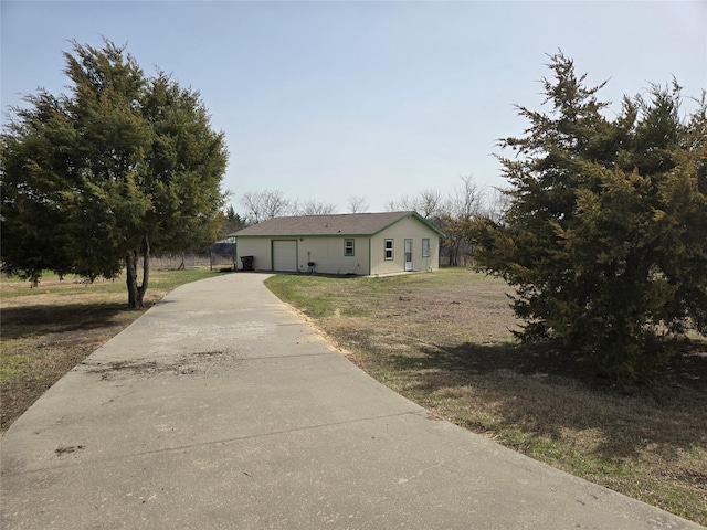 view of front of home featuring concrete driveway, a garage, and a front yard