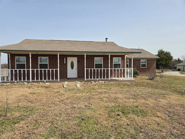 ranch-style home featuring brick siding, covered porch, and a front lawn