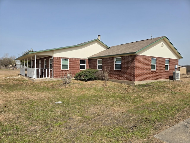 rear view of property with a yard and brick siding