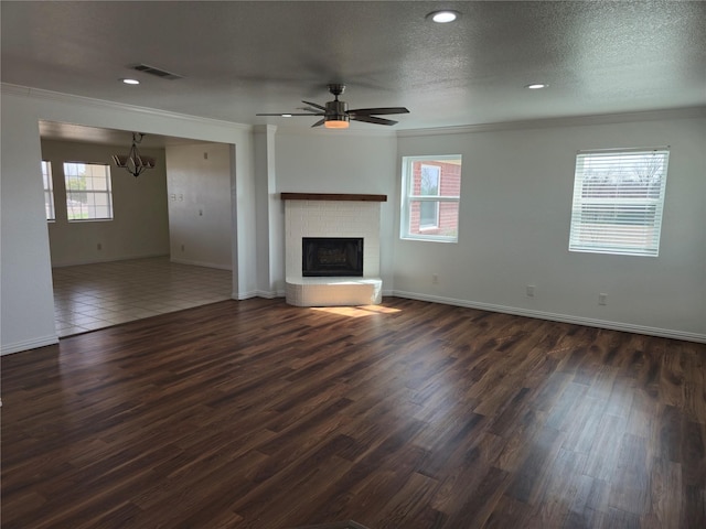 unfurnished living room with visible vents, dark wood-type flooring, ornamental molding, and a textured ceiling