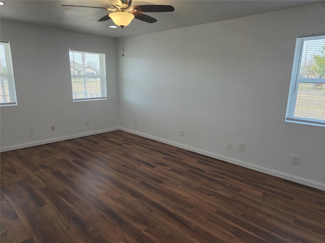 spare room featuring baseboards, dark wood-type flooring, and ceiling fan