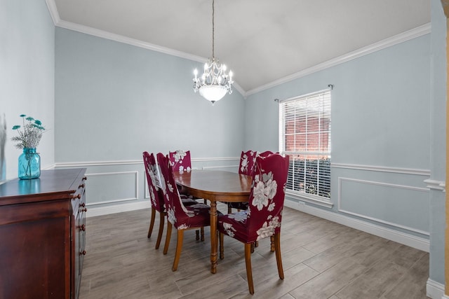 dining room featuring an inviting chandelier, wood finished floors, wainscoting, and ornamental molding