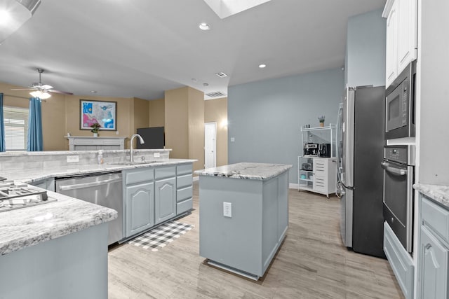 kitchen featuring a sink, light wood-style flooring, appliances with stainless steel finishes, and a center island