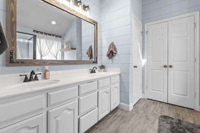 full bath featuring a sink, wooden walls, wood finished floors, and double vanity