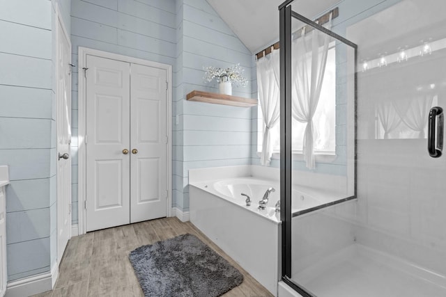 bathroom with a garden tub, a stall shower, wood finished floors, wooden walls, and lofted ceiling