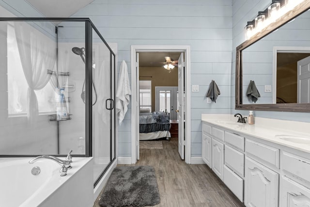 bathroom featuring a sink, wood finished floors, ensuite bath, double vanity, and a bath